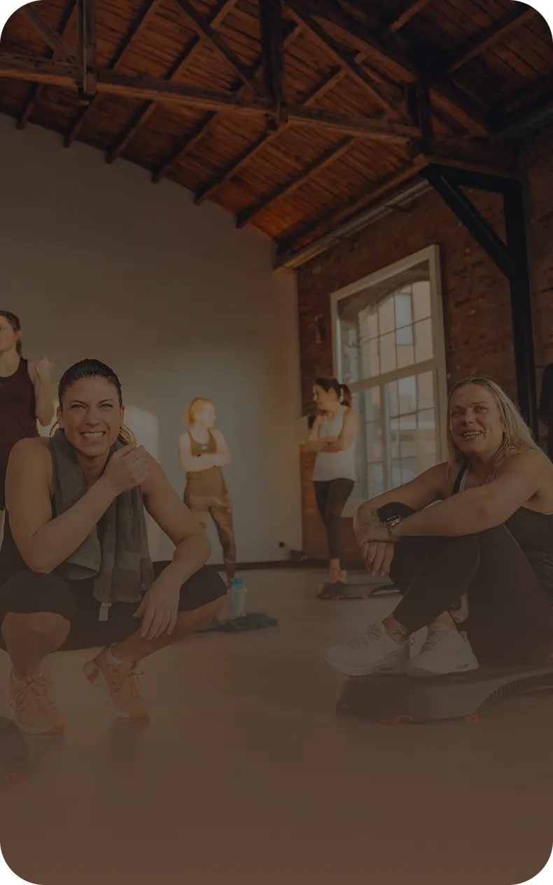 Sportlerinnen machen eine Pause und lachen gemeinsam im Peoples Fitness Studio